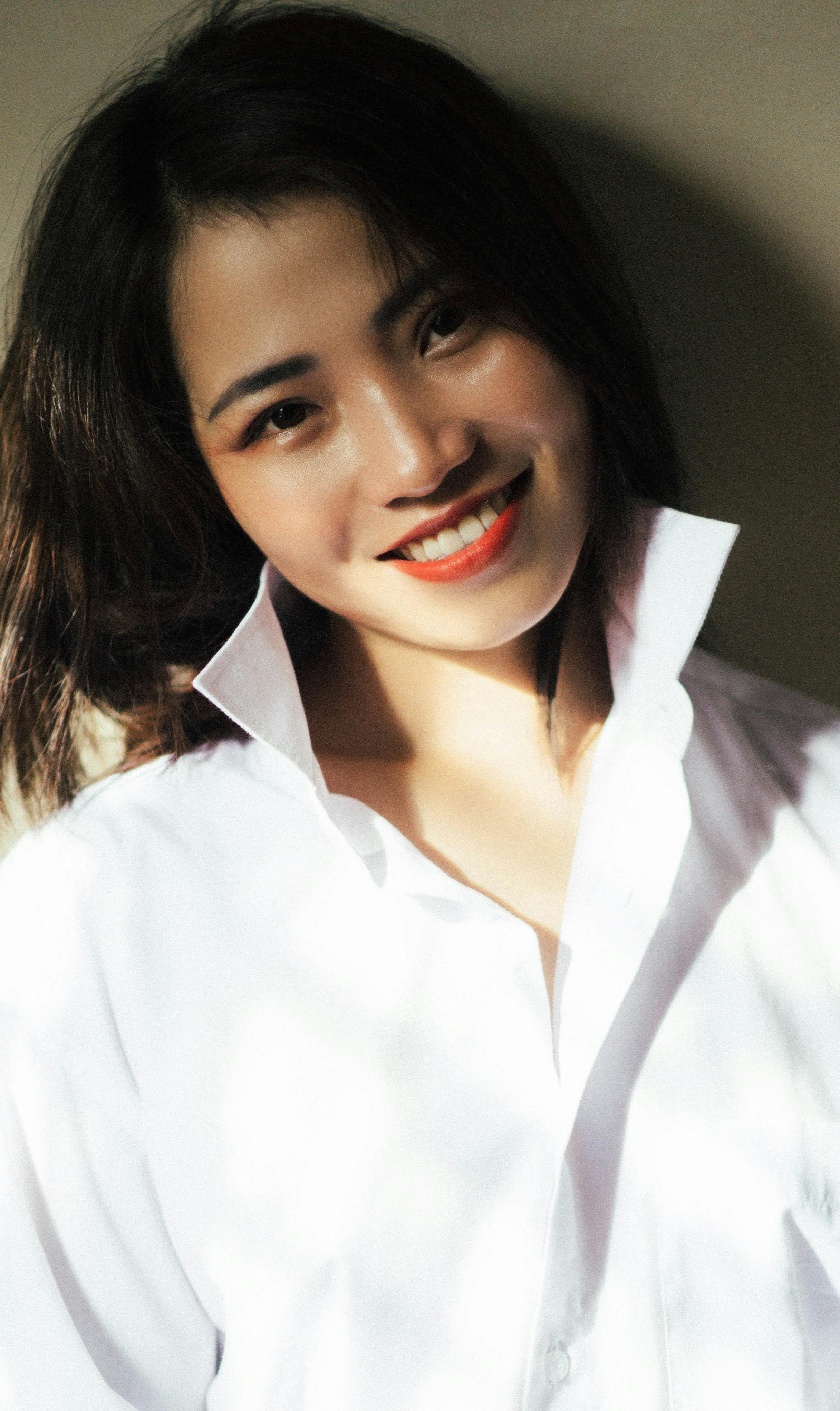 Charming portrait of a smiling woman with long hair wearing a white shirt.