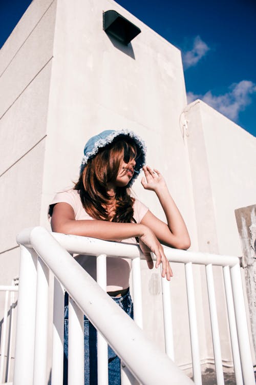 A Woman Wearing Sunglasses Leaning on a Metal Fence