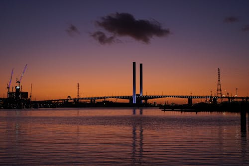 Free A Silhouette of a Bridge Over Water During Sunset Stock Photo