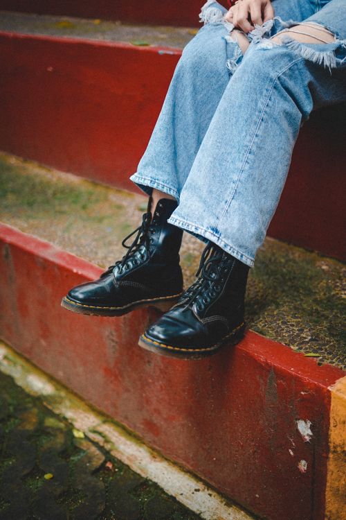 Free Close-up of black leather boots paired with ripped denim jeans on colorful steps. Stock Photo