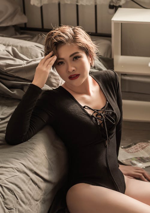 Woman Wearing Leotard Sitting Against the Bed