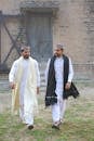 Men in Traditional Clothes Walking on Soil with Green Grass