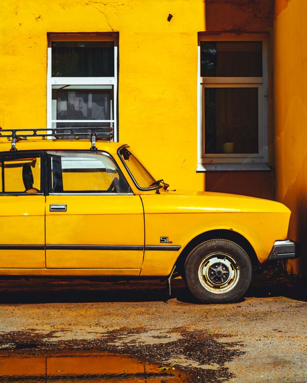 Retro yellow sedan parked against a yellow wall