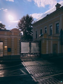 A beautifully lit mansion entrance with intricate wrought iron gate under a clear sky.