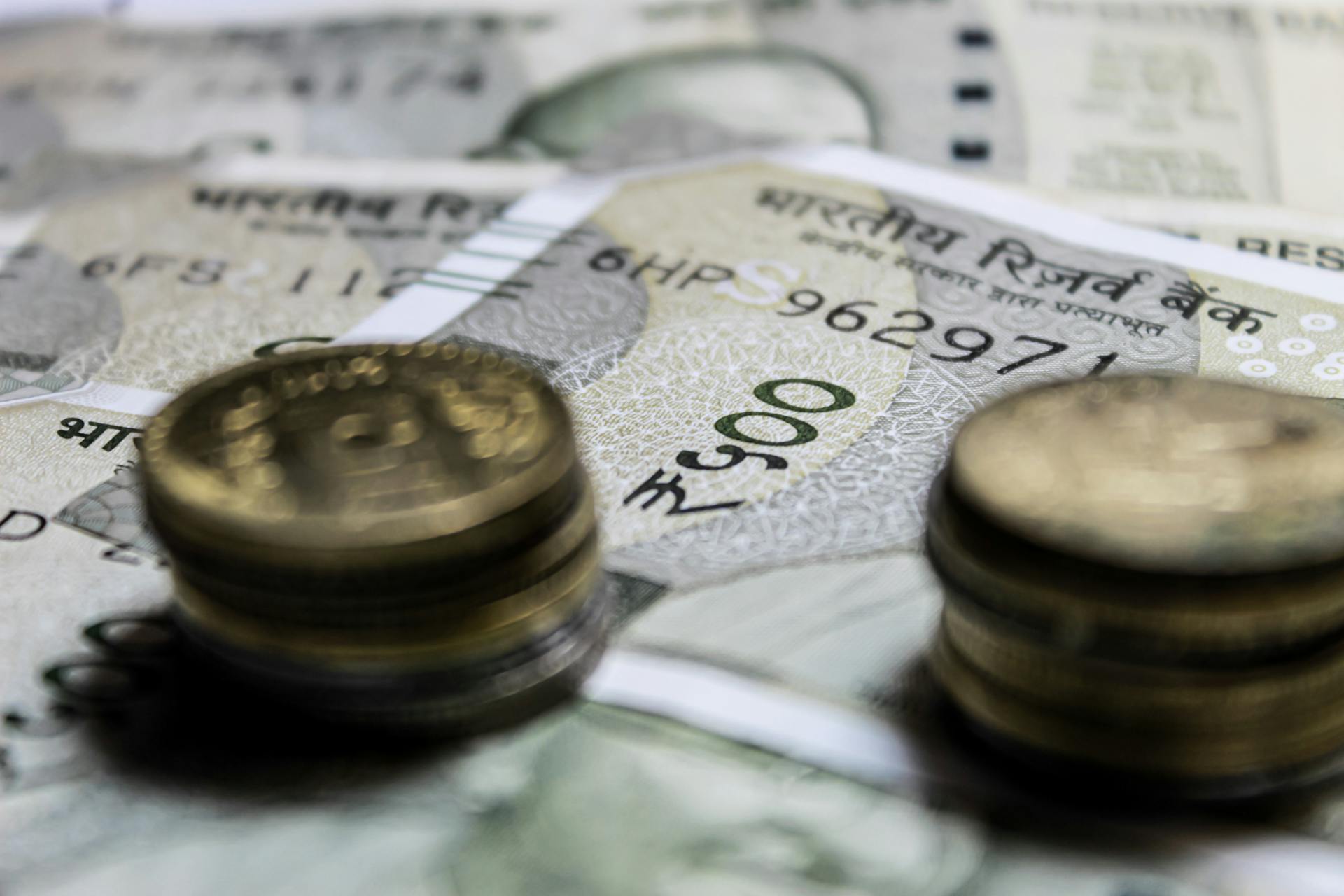 Detailed close-up of Indian rupee coins on top of banknotes, representing finance.