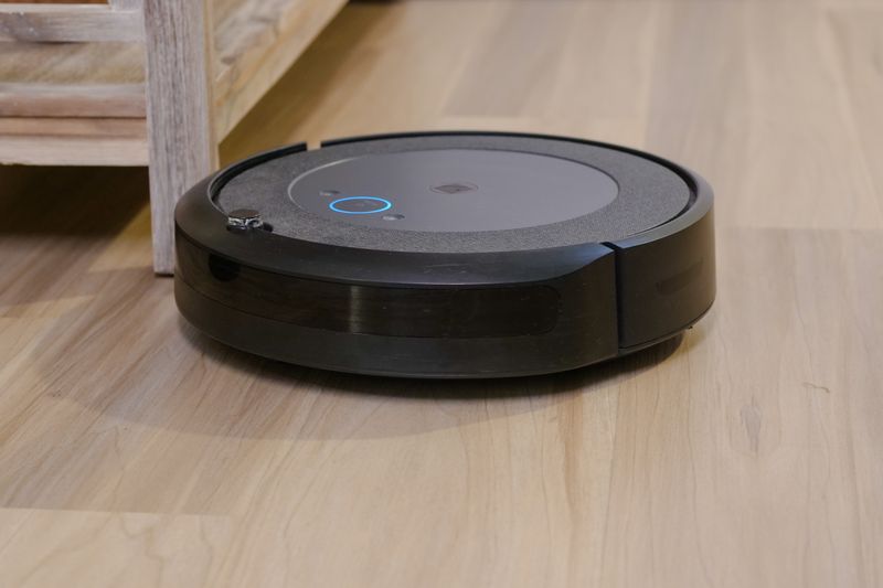 Autonomous vacuum cleaner navigating wooden floor indoors, showcasing smart home technology.