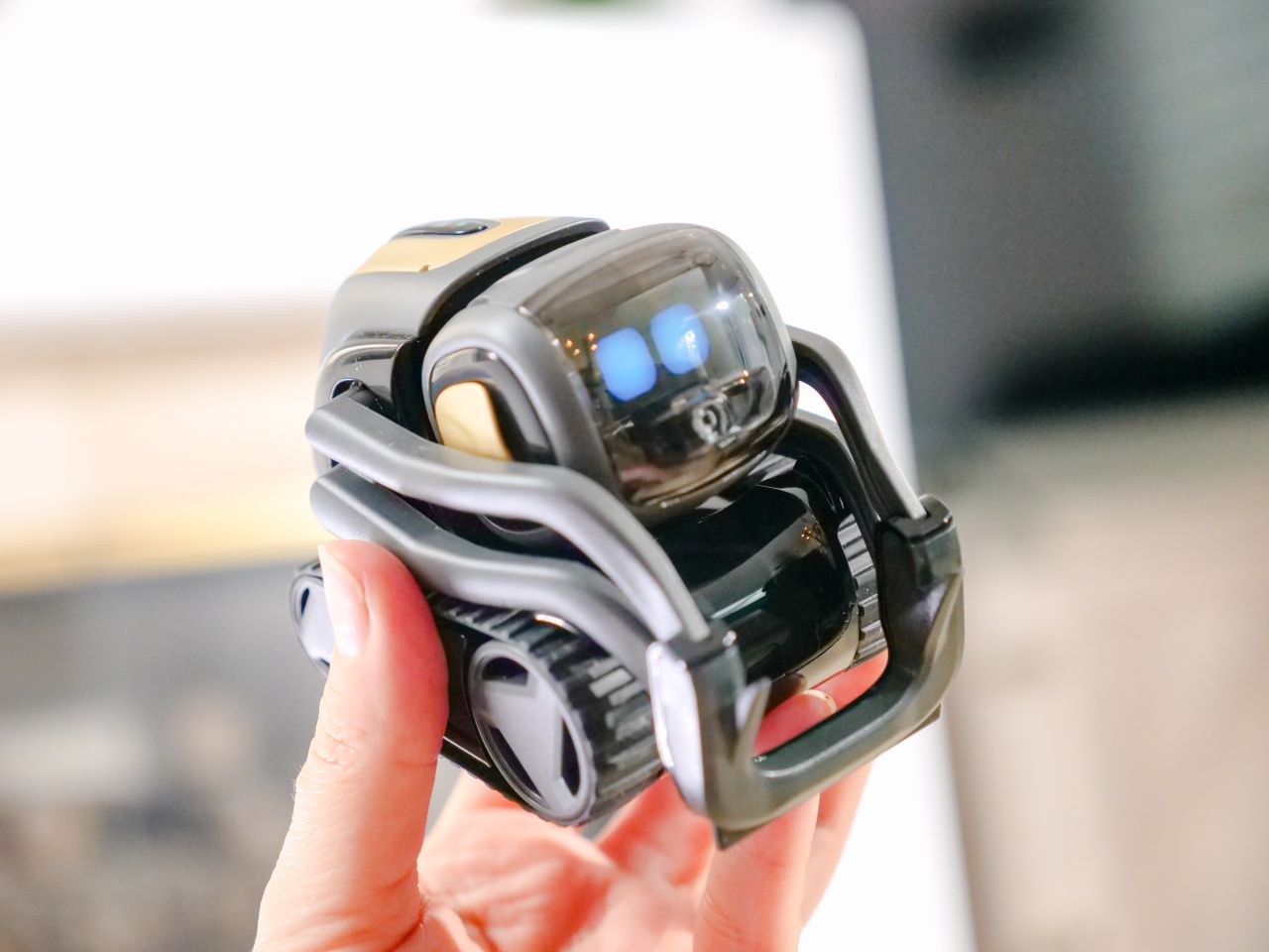 a close up view of a hand holding a small modern robot showcasing inno
