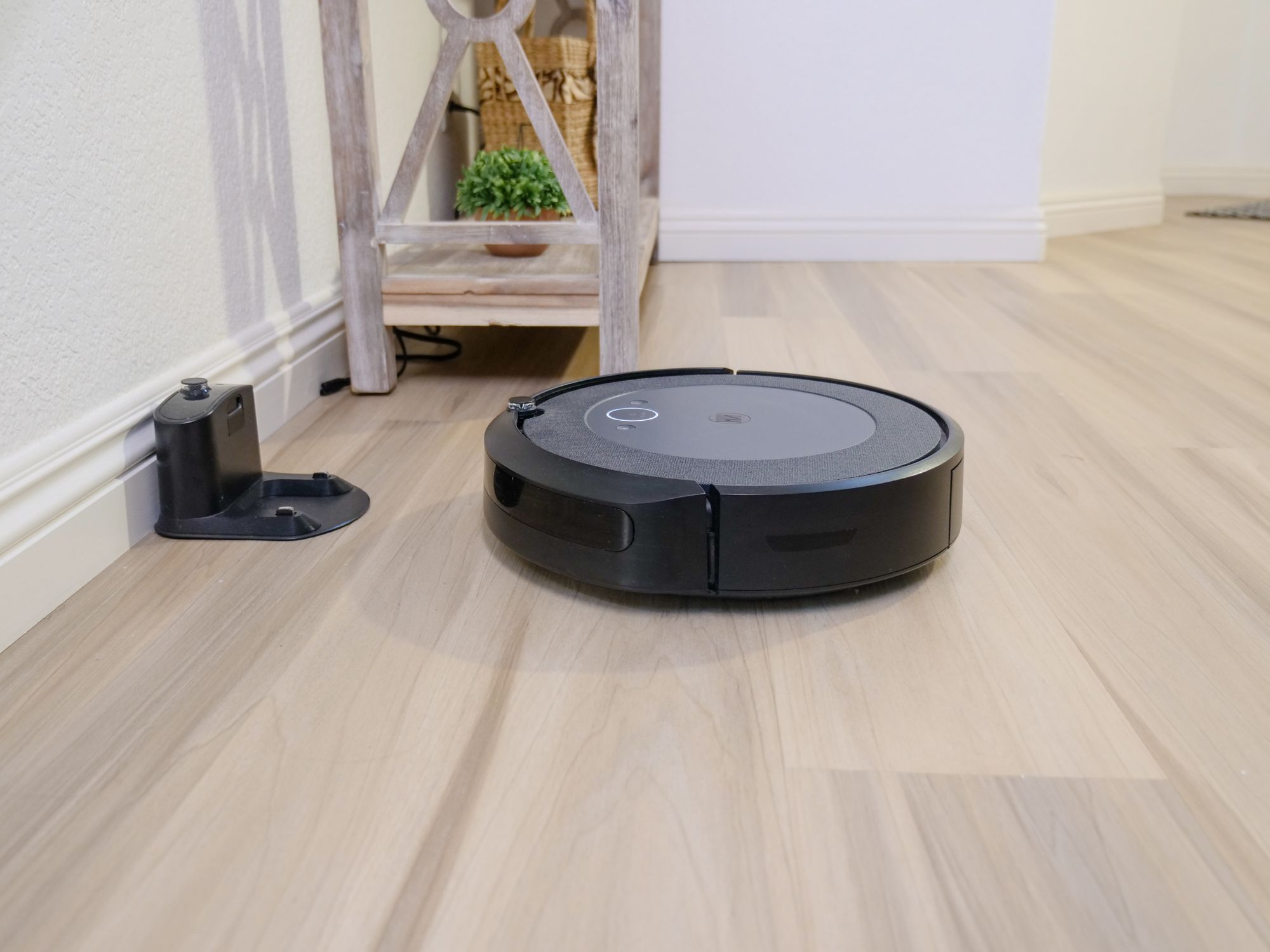 Aspiradora robot circular junto a su base de carga sobre el piso de una sala