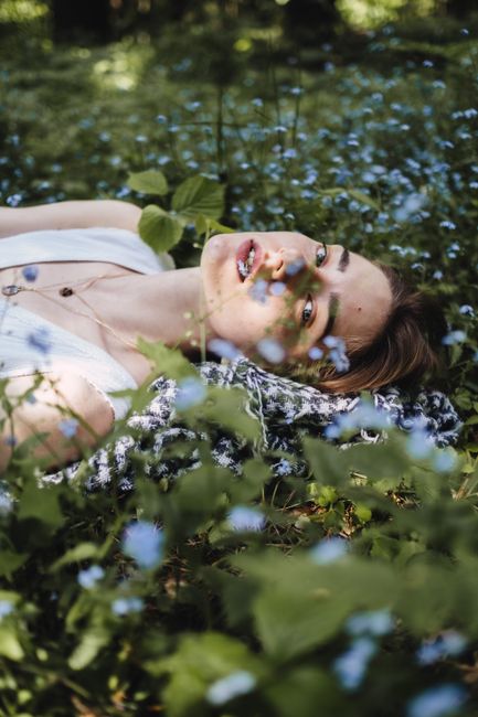 A woman relaxing in a lush forest meadow, surrounded by wildflowers.