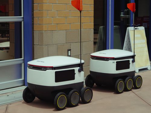 Free Autonomous delivery robots outside building ready for modern food service. Stock Photo
