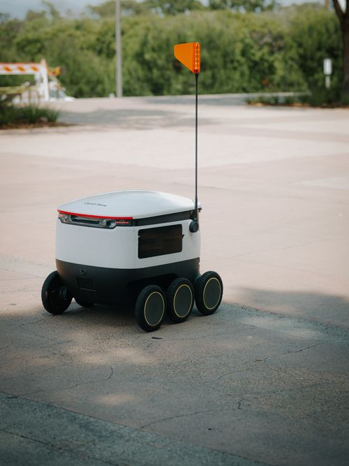 Free Futuristic delivery robot for food transportation on a sunny day. Stock Photo