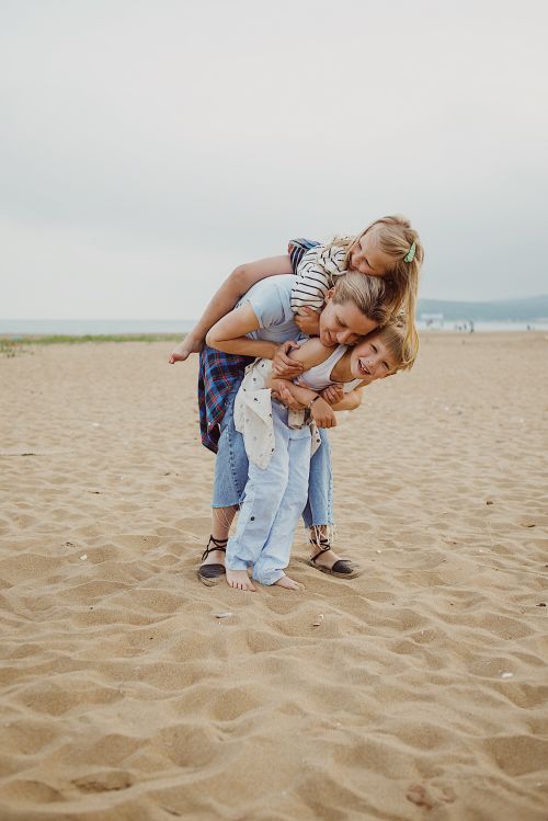 Free A joyful moment with a mother and children playing on a sandy beach. Stock Photo
