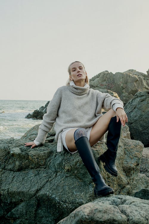 Woman Sitting on a Large Rock on a Seashore 