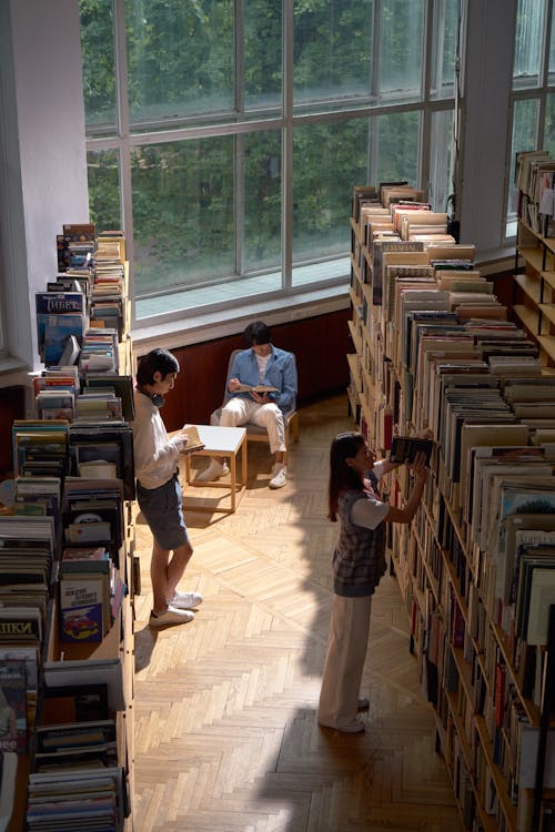 Students in an aisle of a Library between Bookshelves 