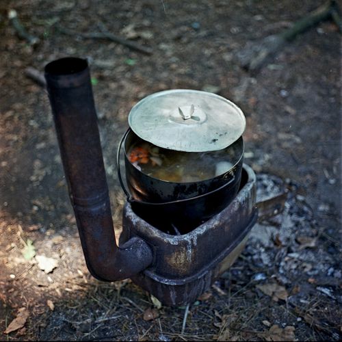 Free A rustic wood stove with a pot of food outdoors in a natural setting. Stock Photo