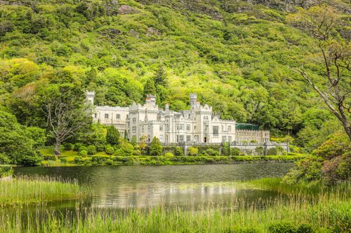 Free Kylemore Abbey nestled in lush greenery by the serene lakeside in Ireland. Stock Photo