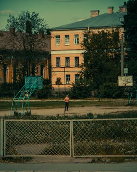 Neglected basketball court in an urban area with a solitary figure in the distance.