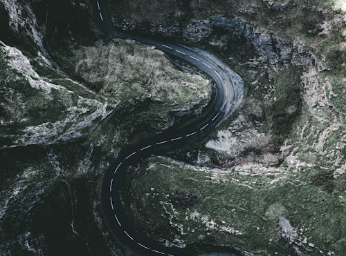 Gray Curvy Road Between Green Rocky Mountains