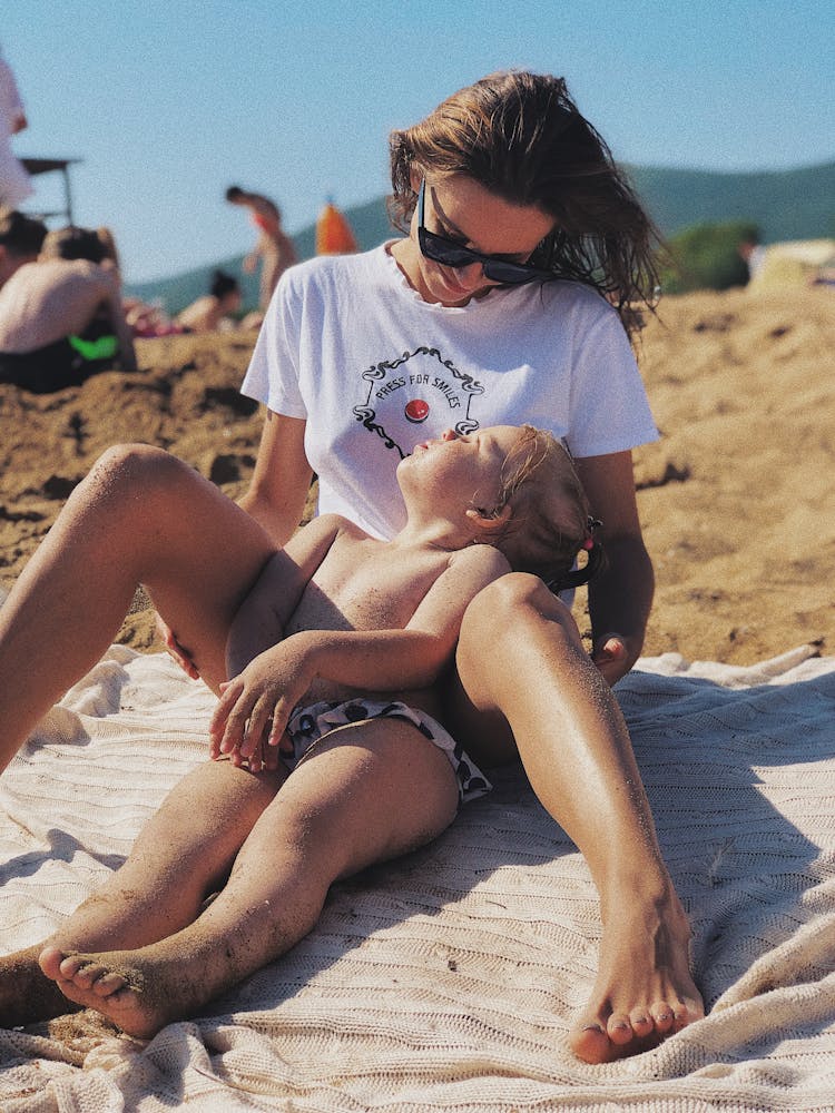 Mother And Child Sitting On White Blanket