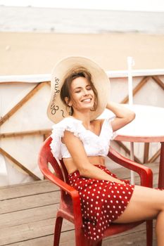 A woman enjoying a sunny day on a beachfront deck, smiling and relaxed.