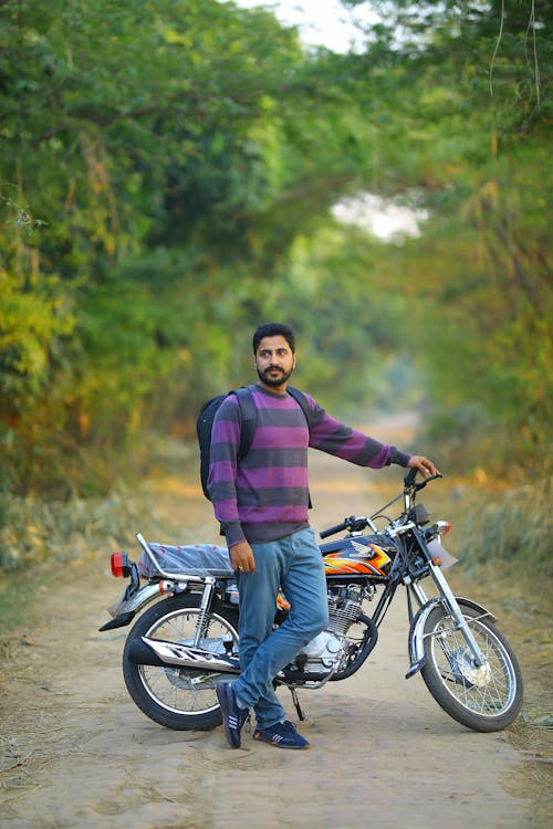 Man and His Motorcycle on a Road in a Forest 