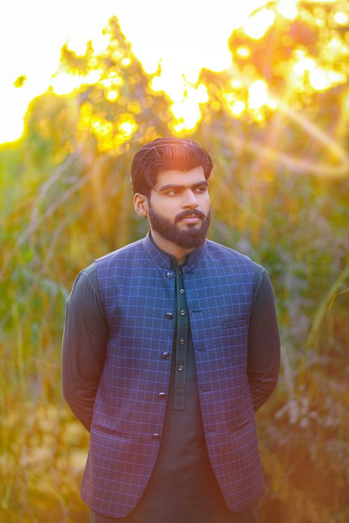 Free A man in traditional attire stands outdoors with a calm expression and sunlit background. Stock Photo