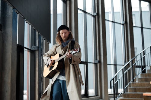 Free Man Wearing Coat Playing Acoustic Guitar Stock Photo