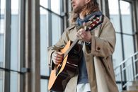 Man in Brown Coat Strumming Brown Acoustic Guitar