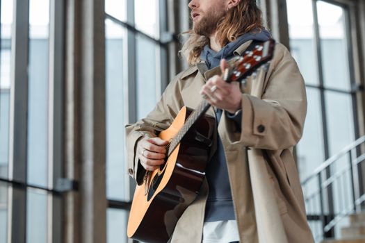 Man in Brown Coat Strumming Brown Acoustic Guitar