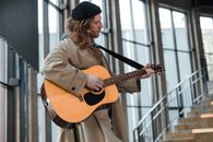 Man in Brown Coat Strumming Acoustic Guitar