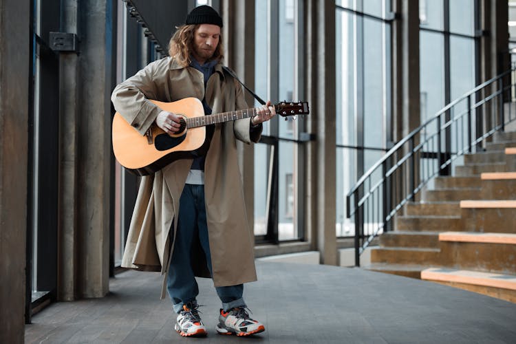 Man In Brown Coat Playing The Guitar