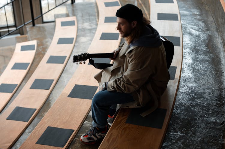 Man Sitting On Brown Wooden Bleachers