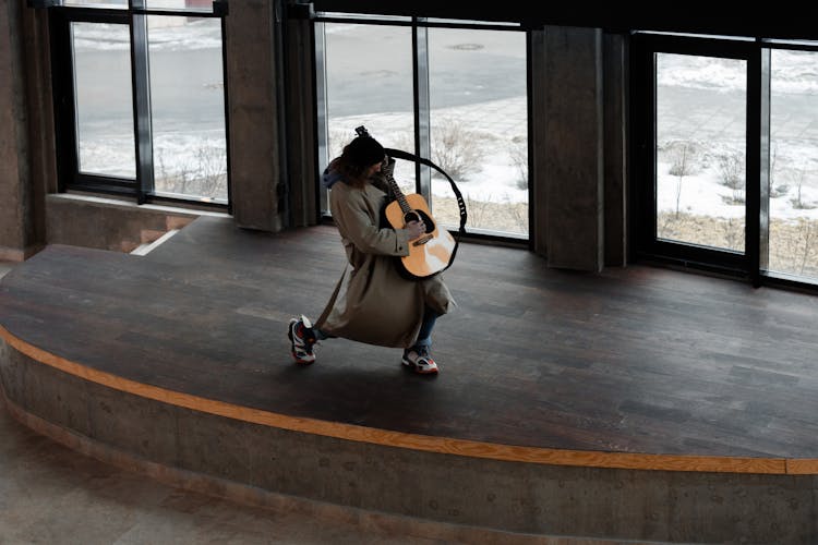 Man On Brown Wooden Stage Playing The Guitar