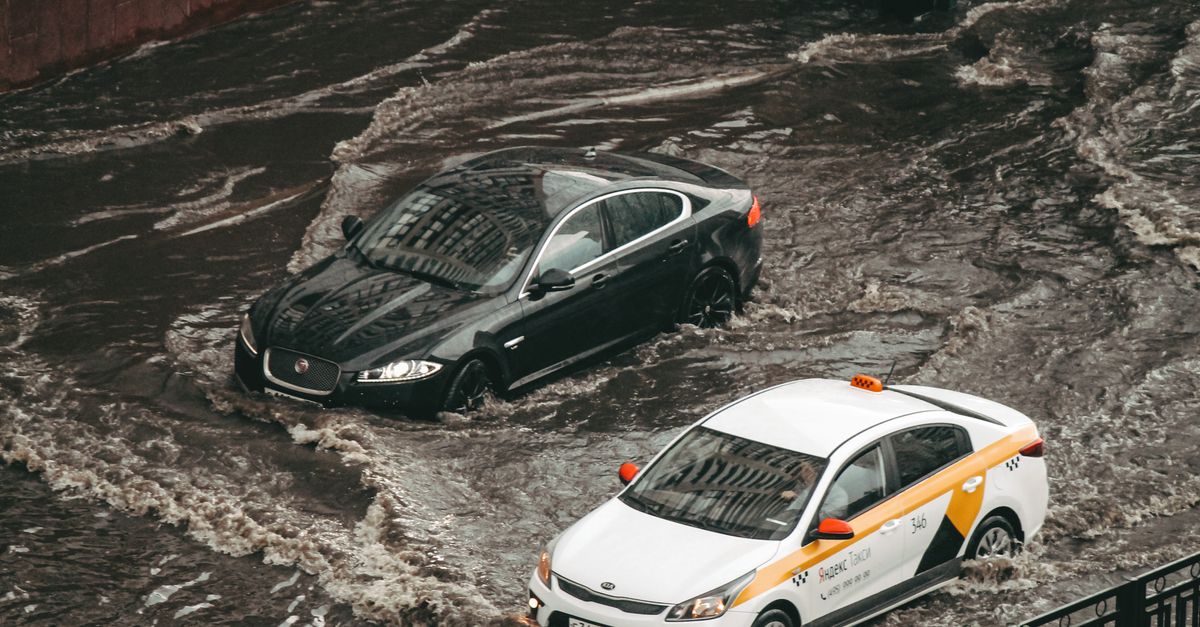 Photo by Sveta K Cars navigating through a flooded city street, showcasing urban chaos and weather impacts.