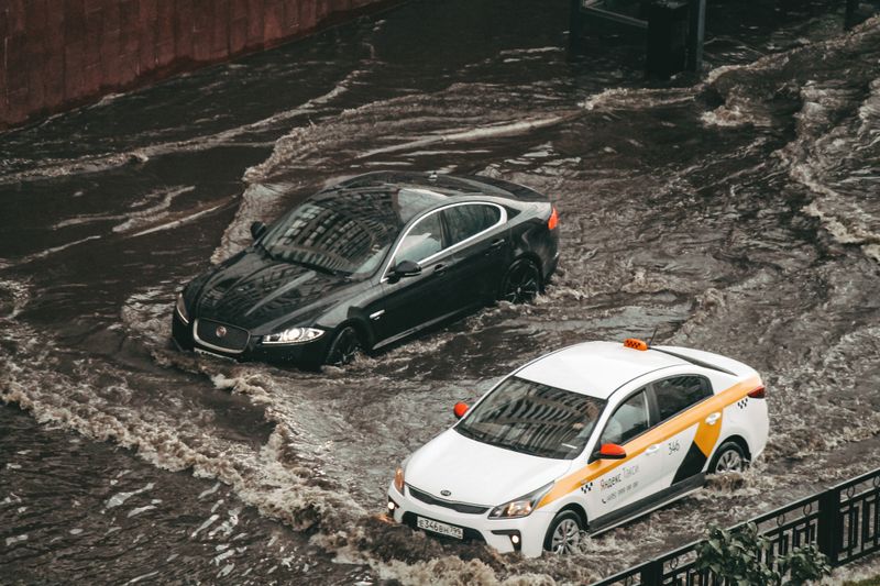 Cars navigating through a flooded city street, showcasing urban chaos and weather impacts.