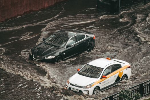 Cars navigating through a flooded city street, showcasing urban chaos and weather impacts.