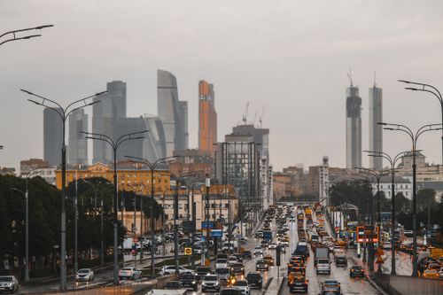 Free A bustling city street with traffic and towering skyscrapers under a cloudy sky. Stock Photo