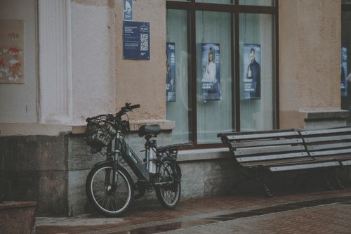 Free Urban street scene with a bicycle parked by benches against a building. Stock Photo
