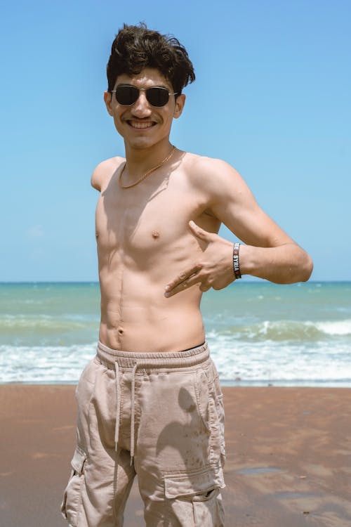 Photo of a Shirtless Man Smiling at the Beach