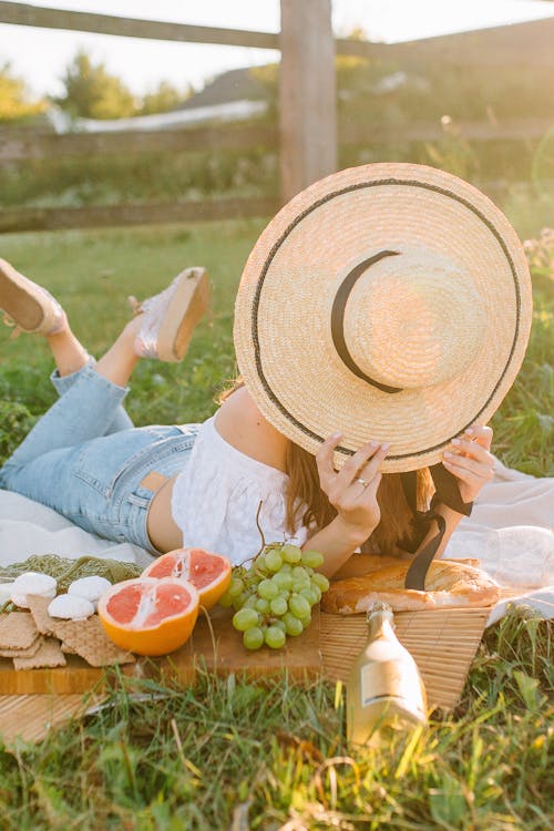 A Woman Lying on a Picnic Blanket Covering Her Face with a  Straw Hat