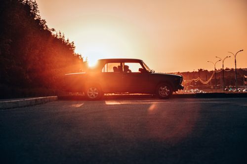 Free A classic car silhouetted against a vibrant sunset, creating a nostalgic scene. Stock Photo