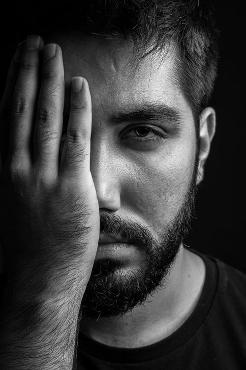 Free Expressive black and white portrait of a man covering half of his face with his hand. Stock Photo