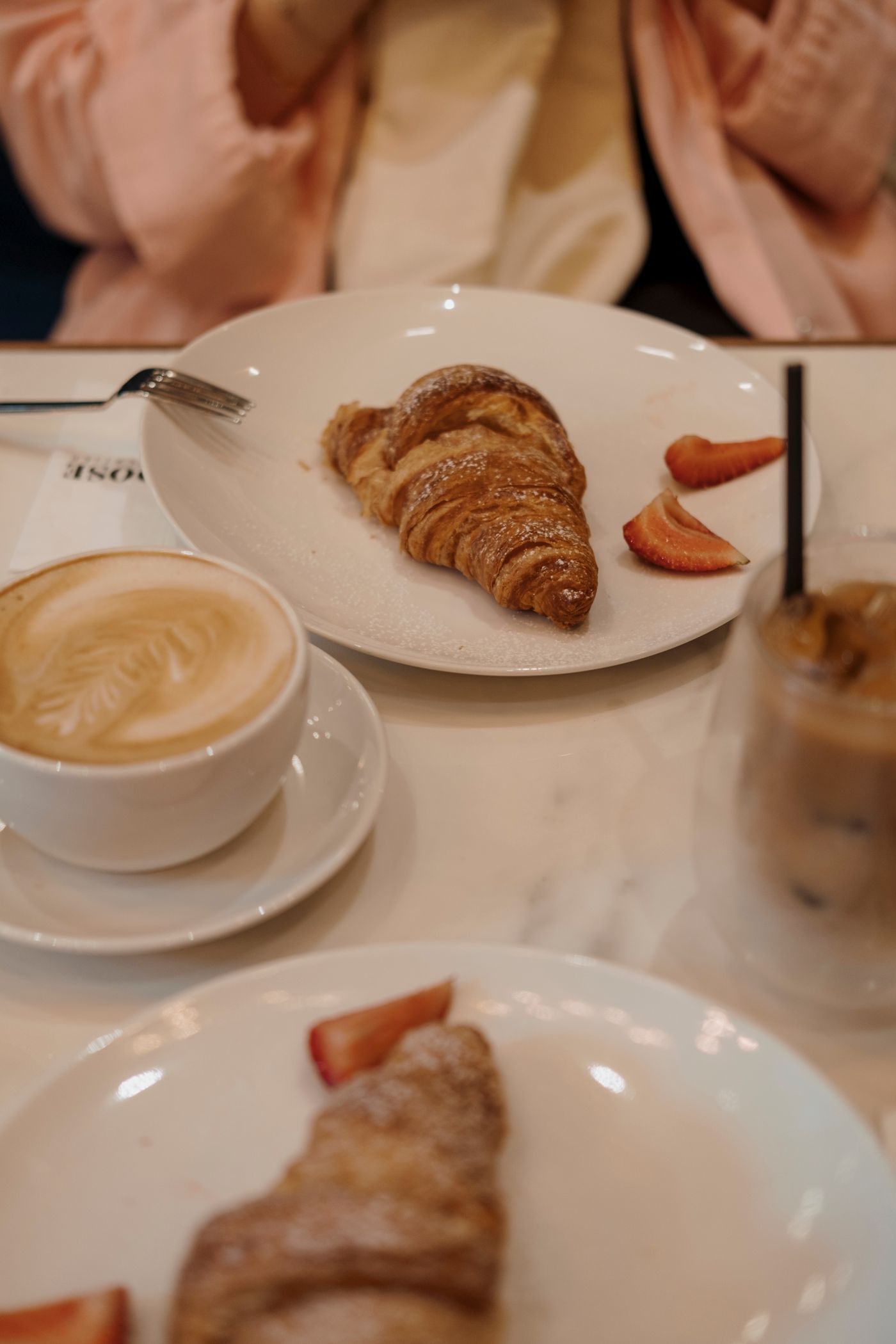 Croissants on a white ceramic plate with a latte coffee, fresh from the cafe bake.