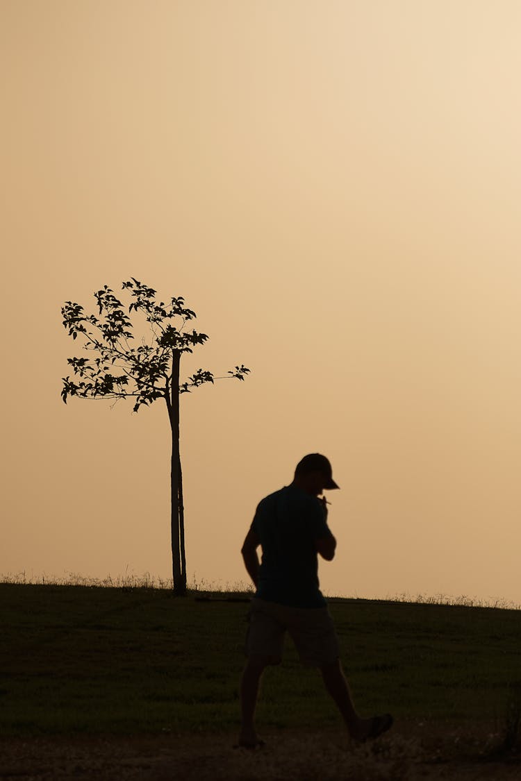 Silhouette Of A Person Walking While Smoking A Cigarette