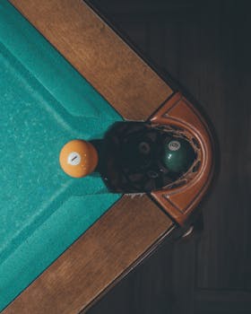 Overhead view of billiard balls near the corner pocket on a pool table.