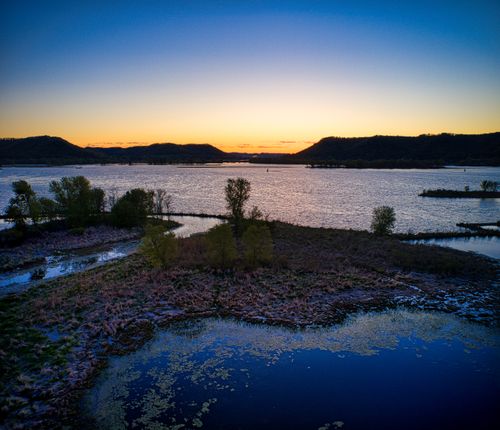 Free Beautiful sunset over the Mississippi River with distant hills and serene water reflection. Stock Photo