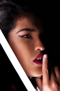 Close-up portrait of a woman with striking makeup and dramatic lighting.