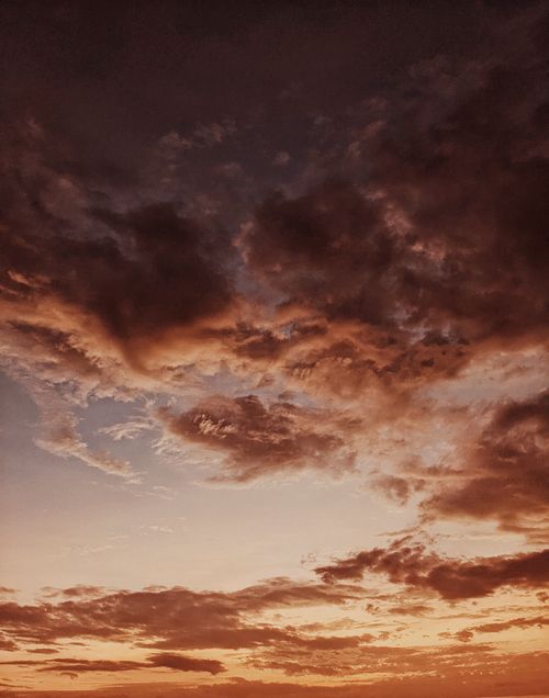 Free Dramatic sky with dark clouds and golden sunset hues, offering a serene nature scene. Stock Photo