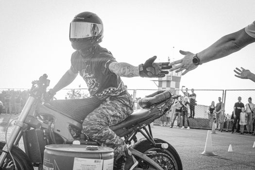 Grayscale Photo of a Person Slapping Hands While Riding a Motorcycle 