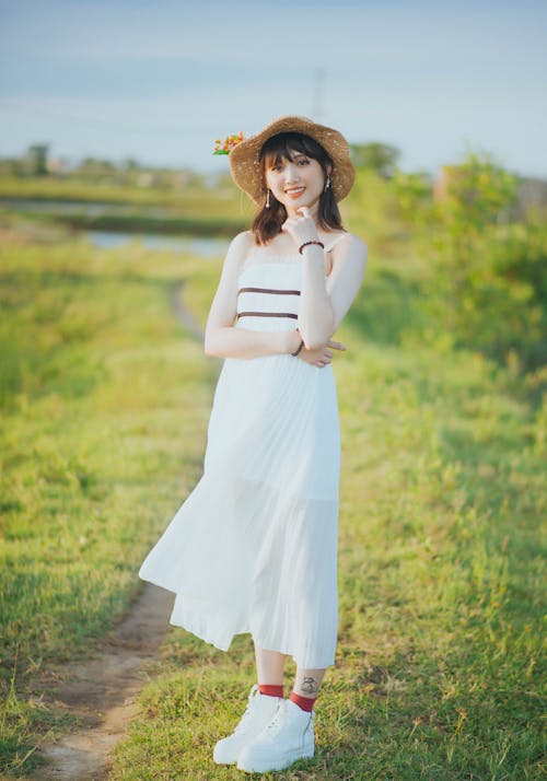A Pretty Woman in White Dress Standing on a Grassy Field
